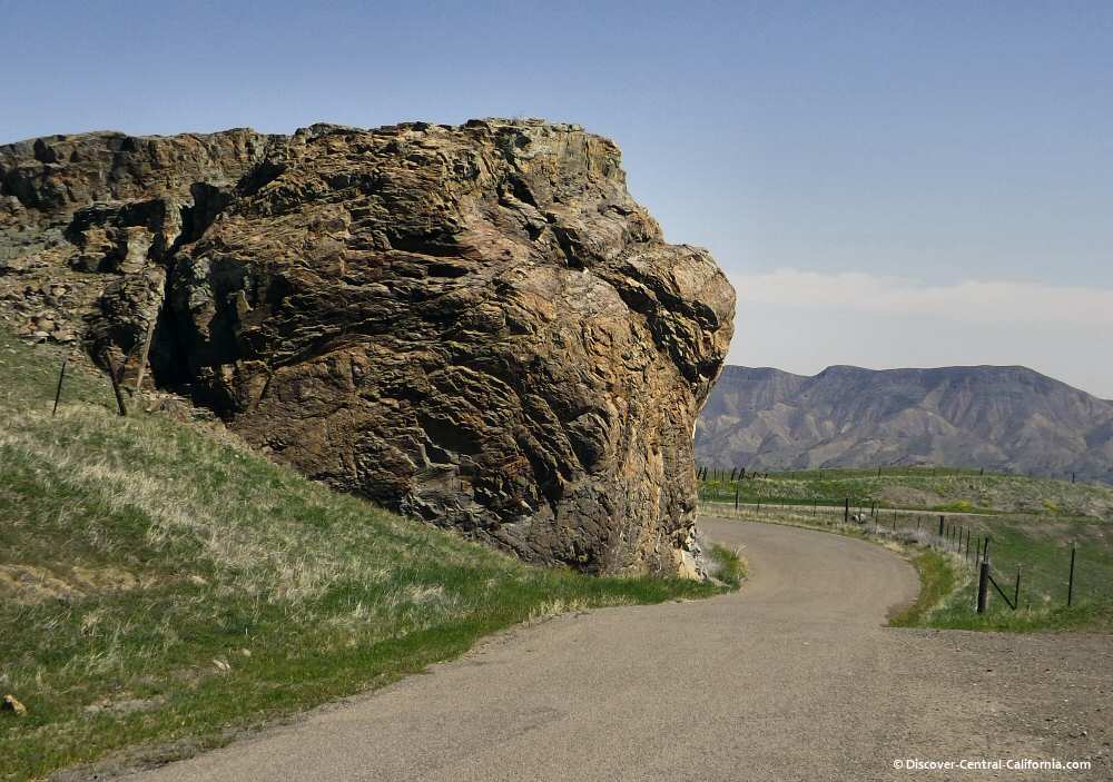 The road winds around a huge boulder