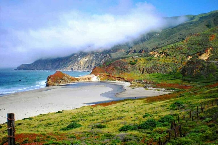 A beach in San Carpoforo with a cliff and a cloudy sky.