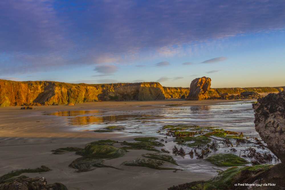 A beach with rocks and sand at sunset.