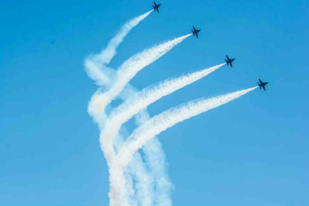 A group of jets flying in formation with white smoke trails.